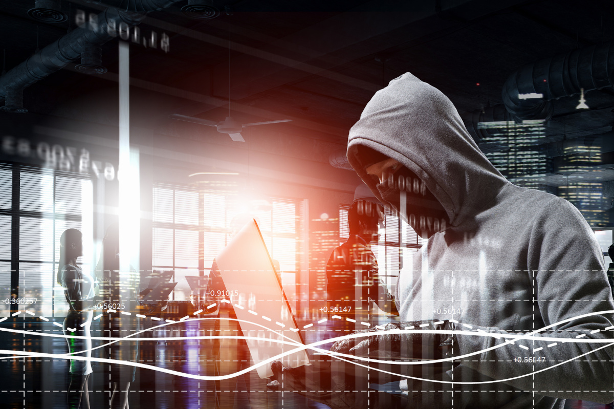 Mysterious man in dark hoodie with laptop computer, hacker cyber security concept.